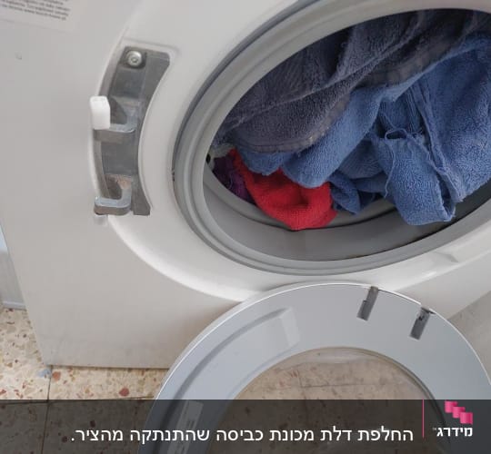 מכונת כביסה עם דלת זכוכית שבורה שמנותקת מהציר